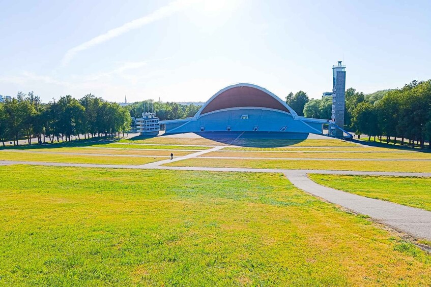 A large stadium with a dome roof, surrounded by a grassy field and a few trees. 2