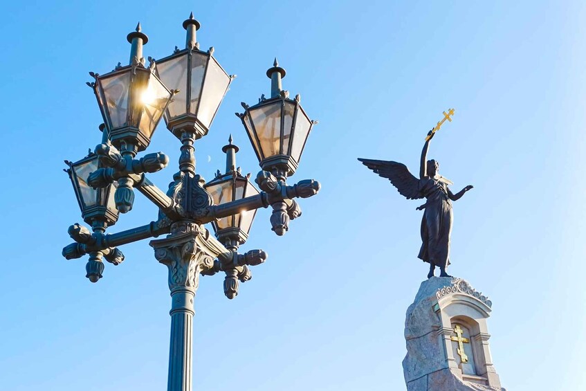A street lamp and a statue of an angel with outstretched wings. 1