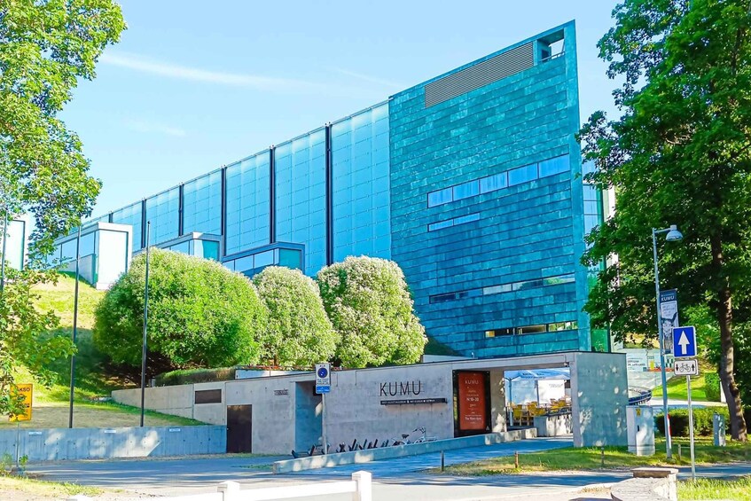 A modern building with a blue facade, surrounded by trees and a clear sky. 4