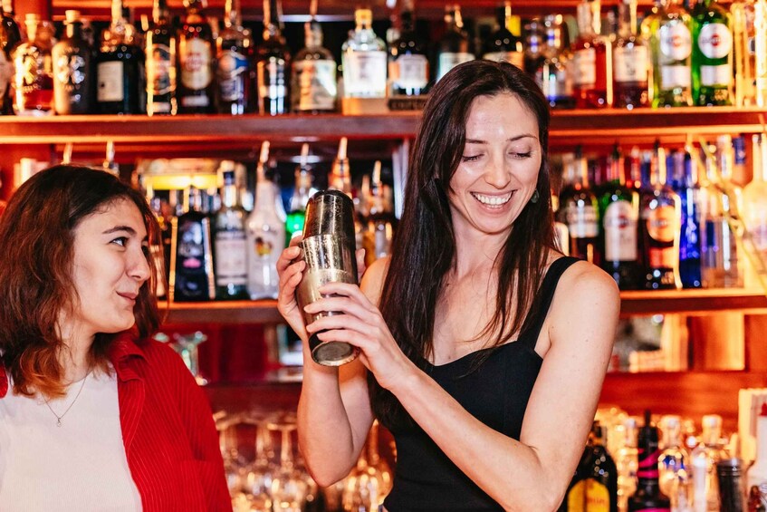 Two people in a bar with shelves of liquor bottles in the background. 3
