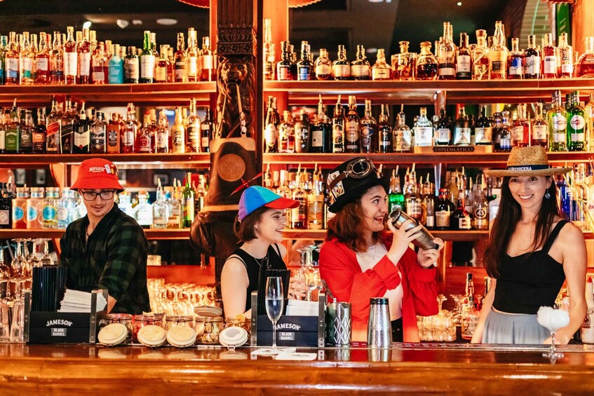 A bar with shelves of liquor bottles, a bartender, and customers. 4