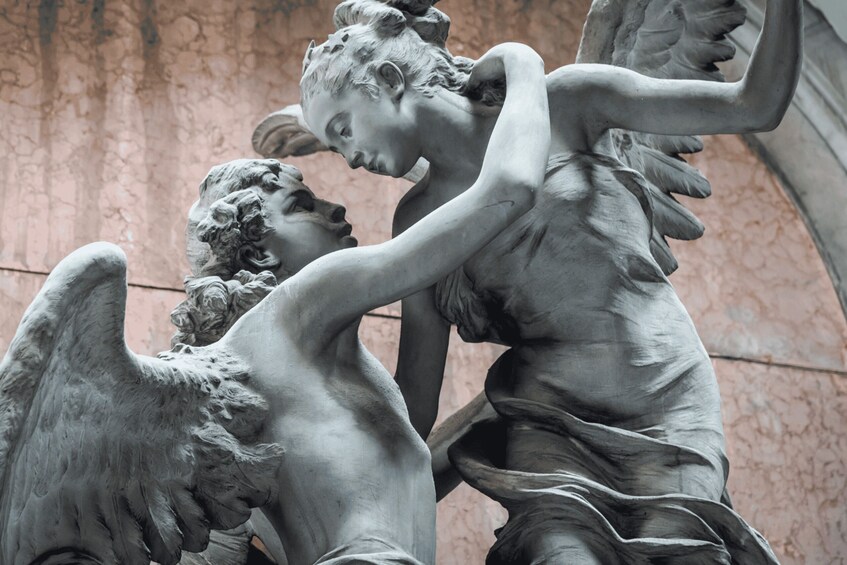 A marble statue of two figures, one with wings, in an indoor setting. 3