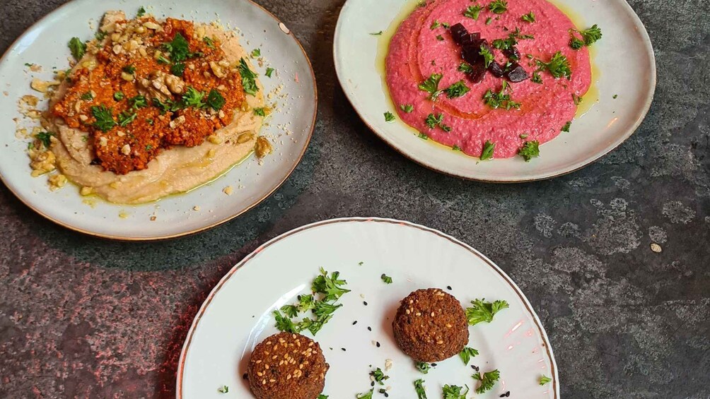 Three plates of food, one with a red sauce, one with a beige sauce, and one with falafel. 5