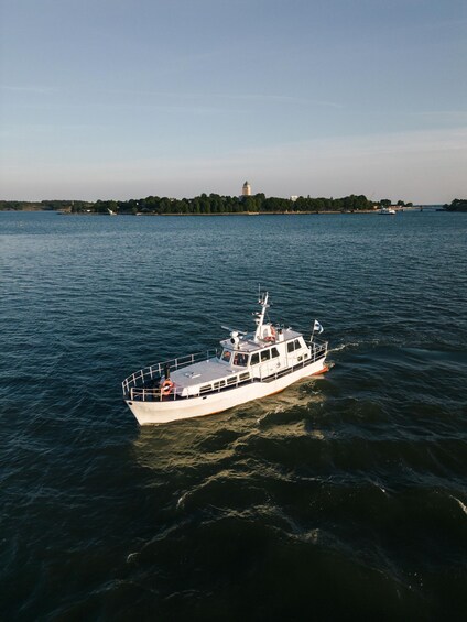 A white boat on a calm body of water with a distant island and a tower. 5