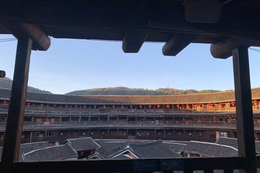 A traditional multi-tiered building with red lanterns, a clear sky, and hills in the background. 5
