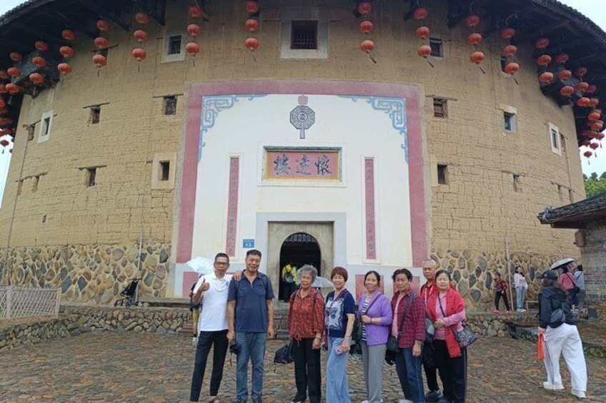 A group of people in front of a traditional building with a stone facade and red lanterns. 2