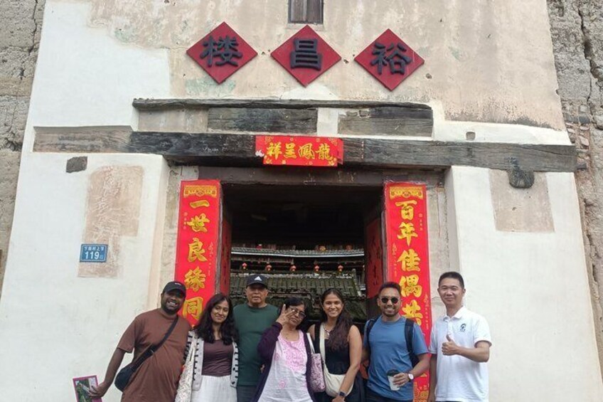 A group of people standing in front of a building with Chinese characters and red banners. 3