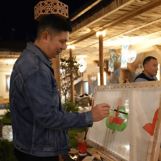 A person painting on a canvas outdoors at night. 5