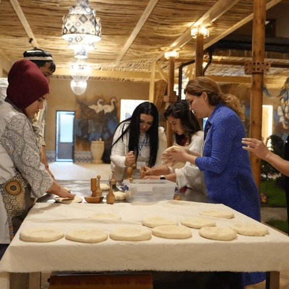 A group of people making bread in a rustic setting with wooden beams and a chandelier. 2