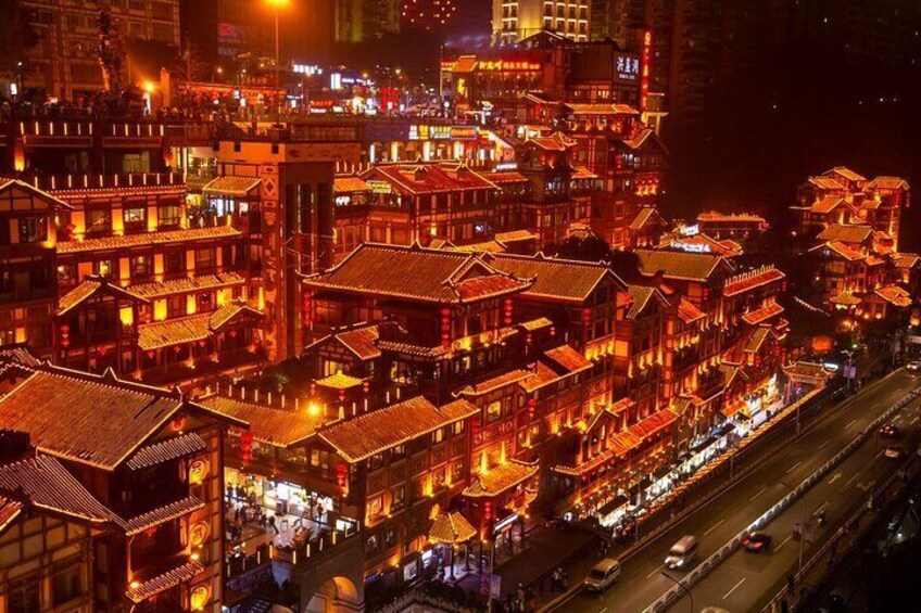 En nattbild av en traditionell kinesisk stad med upplysta byggnader och en livlig gata. 1