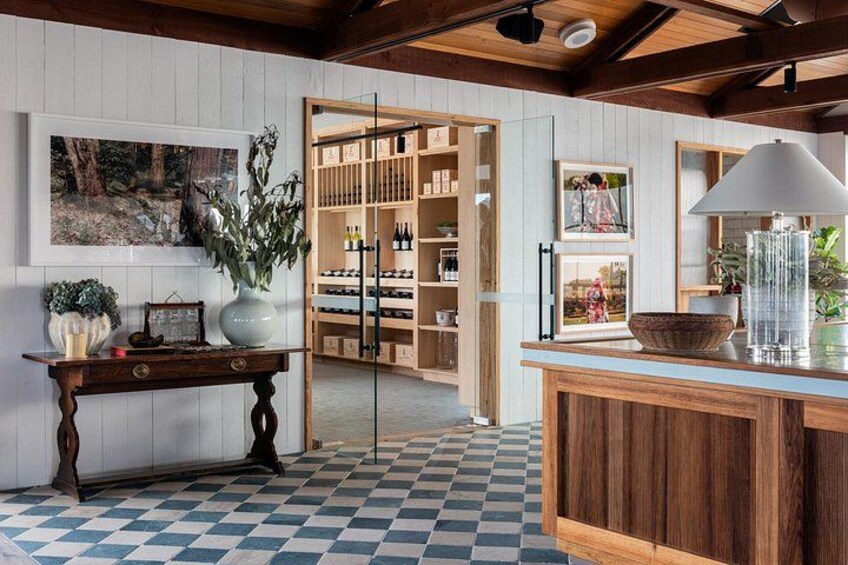 Eine Bar mit Holzboden, karierter Fliesenoptik, einer Blumenvase und einem Weinkühlschrank im Hintergrund. 3
