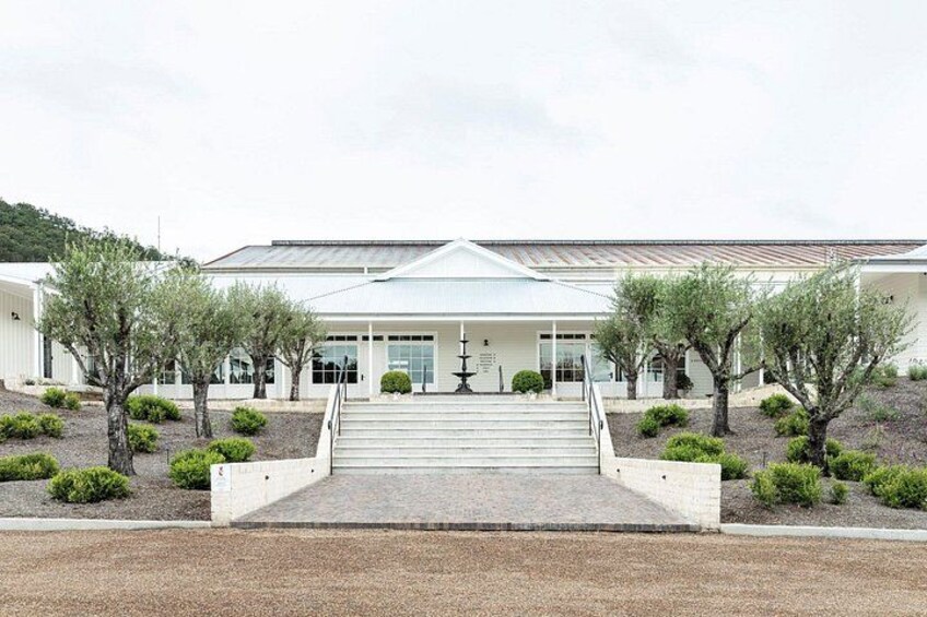 A modern building with a central staircase, surrounded by landscaped areas with trees and shrubs. 4