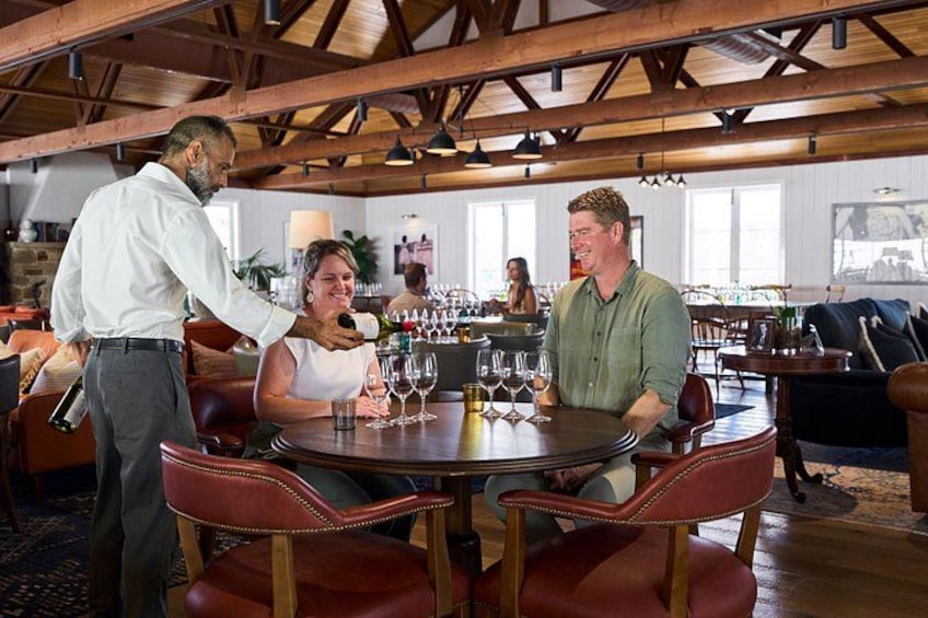 A restaurant interior with wooden beams, round tables, and red leather chairs. 2