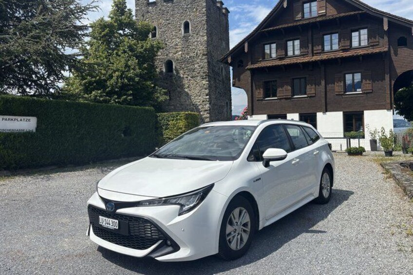 Un auto blanco estacionado frente a un edificio con un letrero que dice "Parkplatz". 4