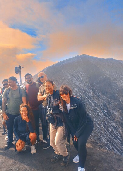 A group of people posing in front of a mountain with a sunset in the background. 4