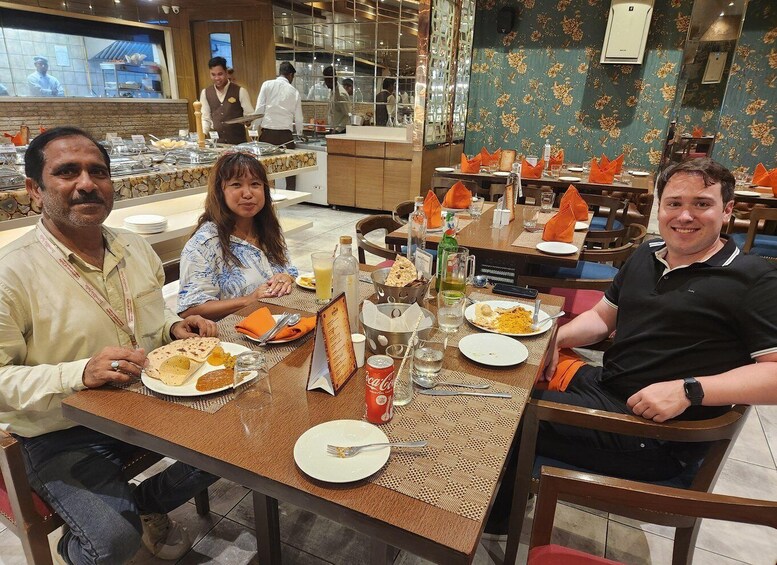 Three people dining at a restaurant with a buffet and a counter visible in the background. 3
