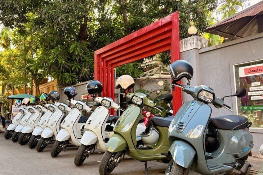 A row of scooters parked in front of a red gate. 3