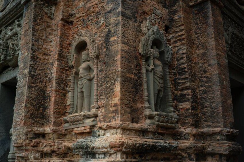 Ancient stone carvings of figures on a brick structure. 2