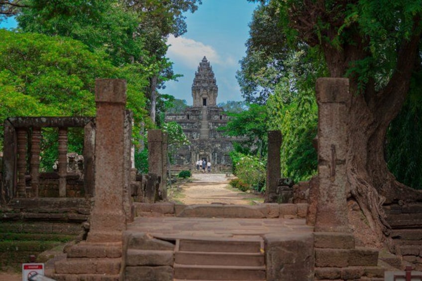 A temple complex with stone pathways, large trees, and a central structure. 1