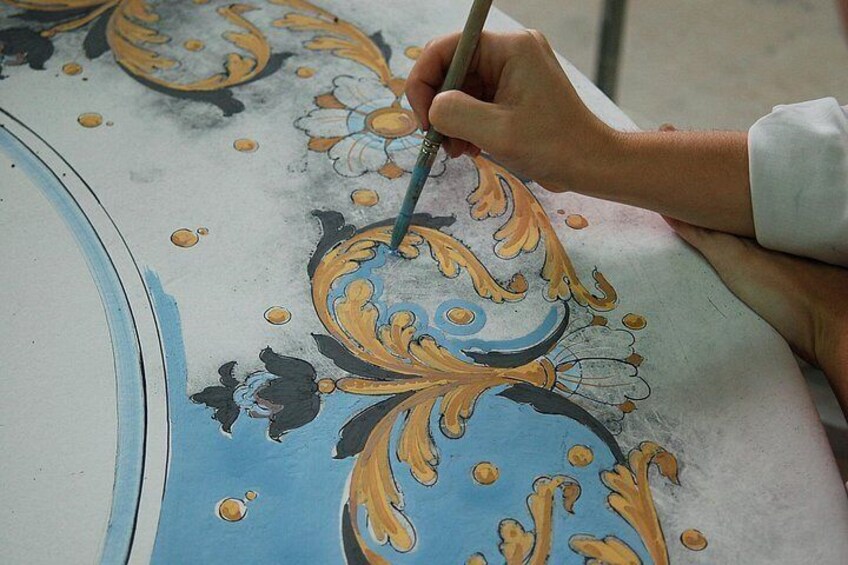 A person painting a floral pattern on a surface. 2