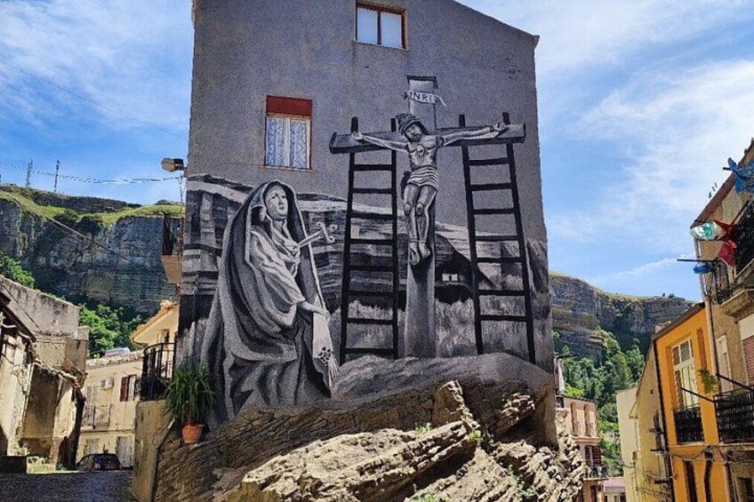 Une fresque représentant Jésus-Christ sur la croix, peinte sur un bâtiment dans un village. 4