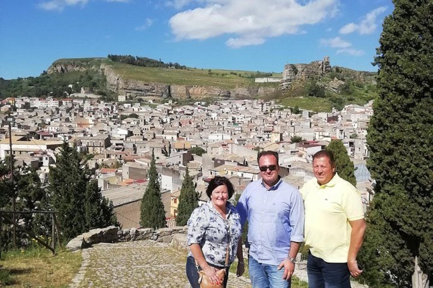 A group of people standing on a hill overlooking a town with buildings and a rocky hill in the background. 3
