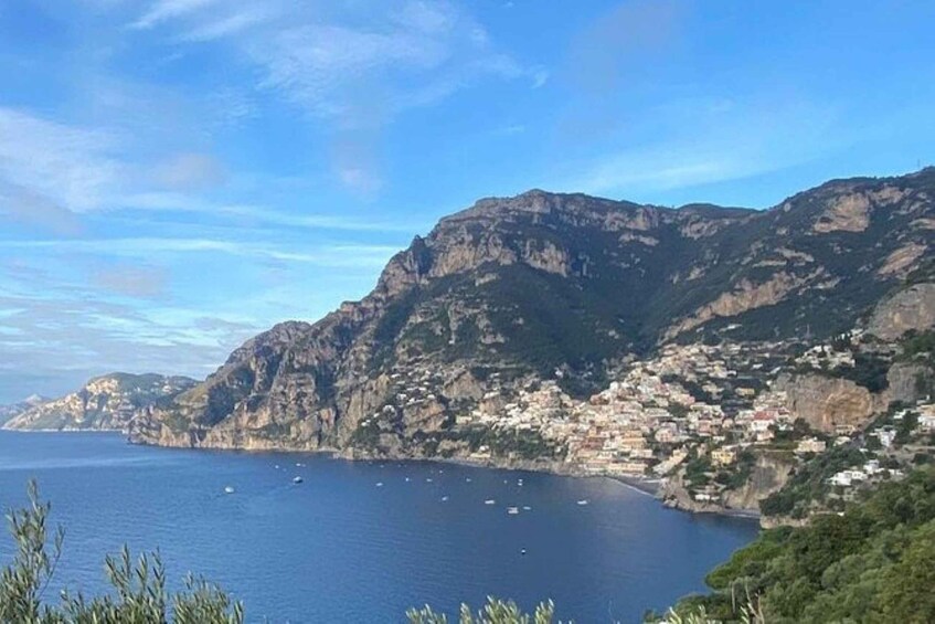 A coastal town with buildings along the cliffs, a clear blue sea, and boats in the water. 3