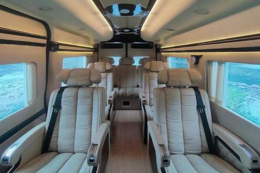 Interior de tren con asientos de cuero color beige, paneles de madera y ventanas amplias. 2