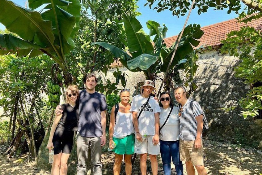Un grupo de personas en un entorno natural, con árboles y un muro de piedra al fondo. 5