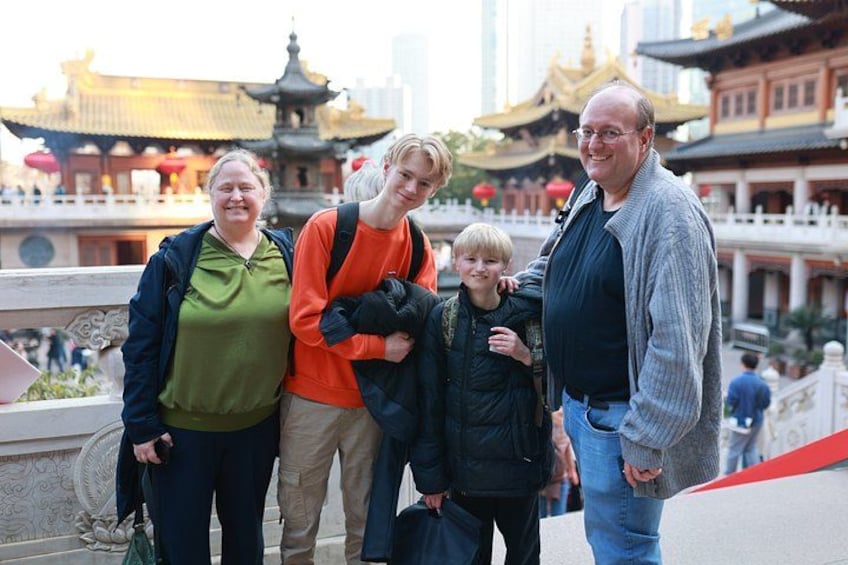 A family of four at a historical site with traditional architecture, including a pagoda and a bridge. 1