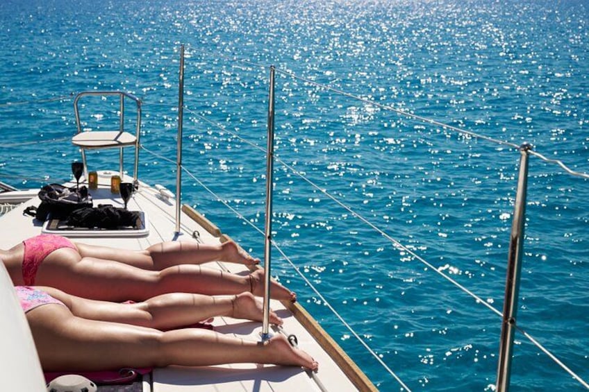 A boat with people sunbathing on deck, calm sea, and clear sky. 2