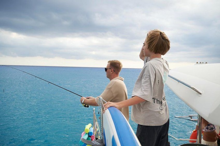 Two people fishing on a boat with a clear view of the ocean. 5
