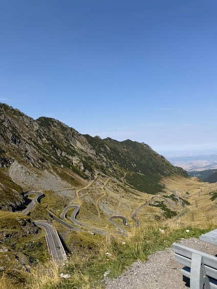 A winding mountain road with rocky terrain and sparse vegetation. 2