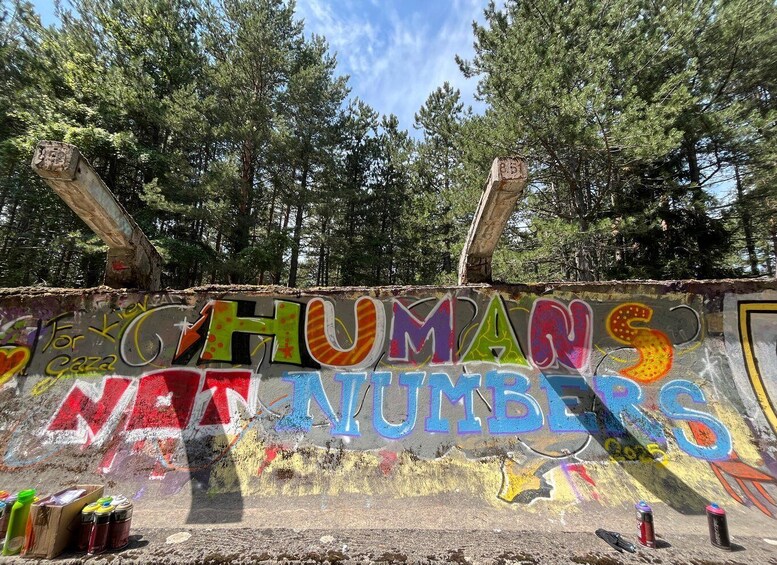 A graffiti wall with the phrase "HUMANS ARE NUMBERS" in colorful letters. 5