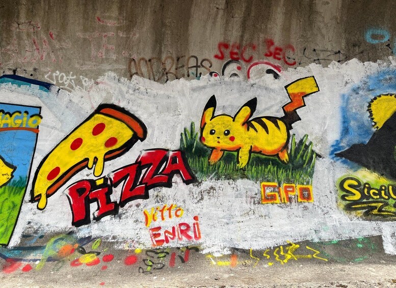 A wall with graffiti, including a large pizza slice and a Pikachu character. 2