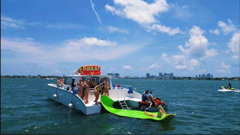 A boat with a 'Great' sign, people on a green raft, and a jet ski in the background. 1