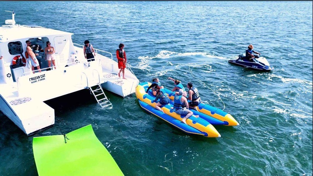 A boat named 'CRUZAN CAT' in Miami, Florida, with people on inflatable rafts and a jet ski in the water. 3