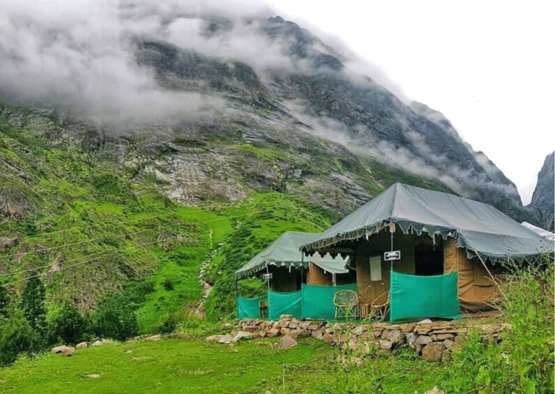 A mountain campsite with tents and a stone wall. 5
