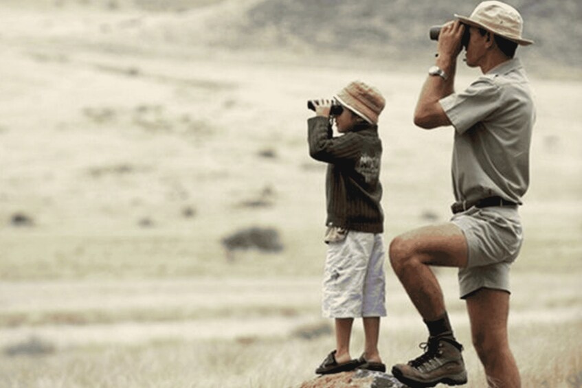 A man and a child using binoculars in a field. 3