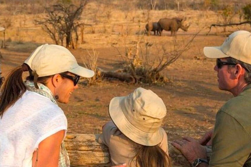 Three people observing wildlife in a dry, open landscape. 4