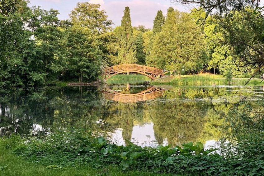 A wooden bridge over a pond surrounded by lush greenery. 2