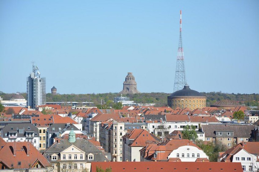 A cityscape with red-roofed buildings, a prominent church dome, and a tall communication tower. 3