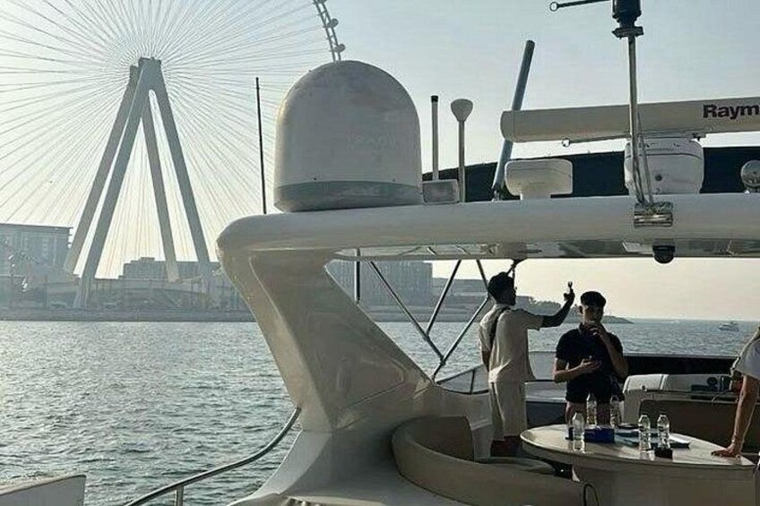 A boat with a radar dome, a person standing on the deck, and a Ferris wheel in the background. 3