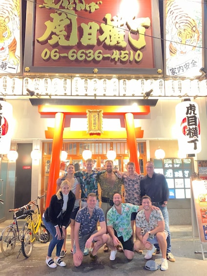 A group of people posing in front of a building with a tiger sign and a phone number. 5
