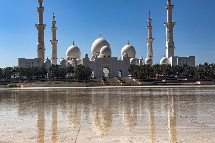 A large mosque with multiple domes and minarets, surrounded by palm trees and a reflecting pool. 3
