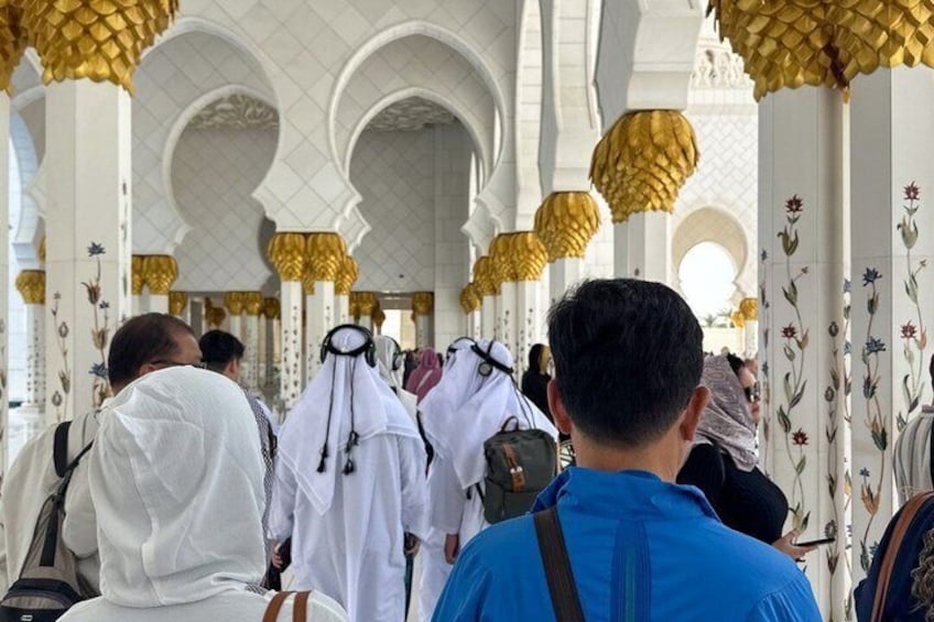 A mosque interior with white columns, golden lanterns, and floral patterns. 2