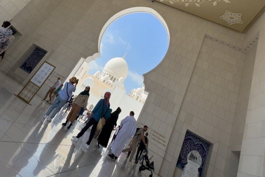 A group of people inside a building with a large circular skylight and a domed structure in the background. 4