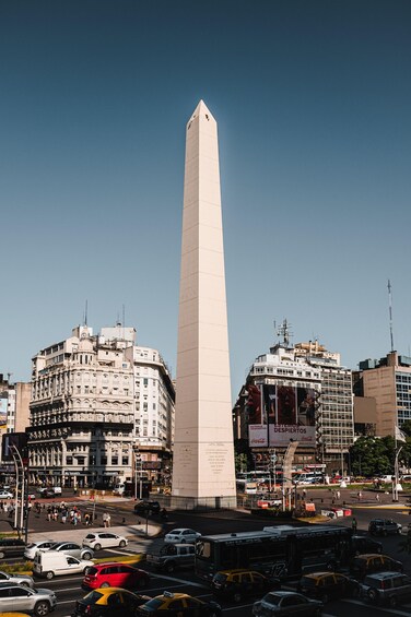A tall obelisk in a city square surrounded by buildings and busy streets. 2