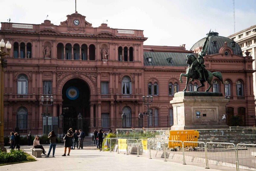A pink building with a statue of a man on a horse in front. 5