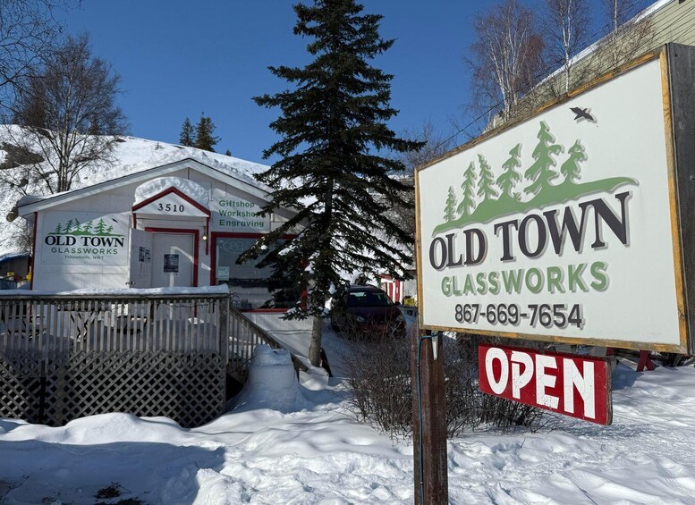 A snow-covered building with a sign for Old Town Glassworks, a workshop, and a contact number. 3